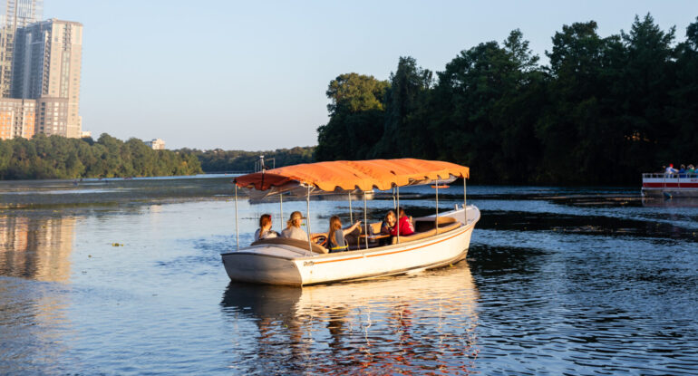 A covered boat cruising Lady Bird Lake in Austin