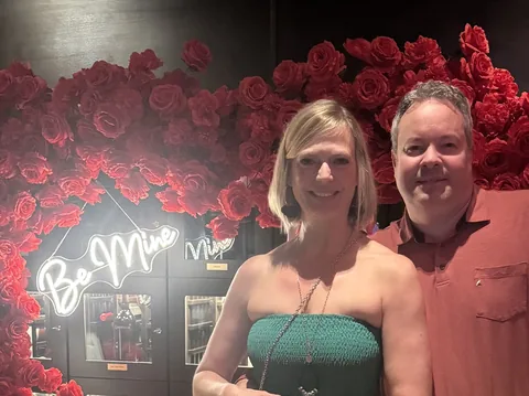 Mark and Jen celebrating Valentine’s Day beside a red rose display in downtown Austin
