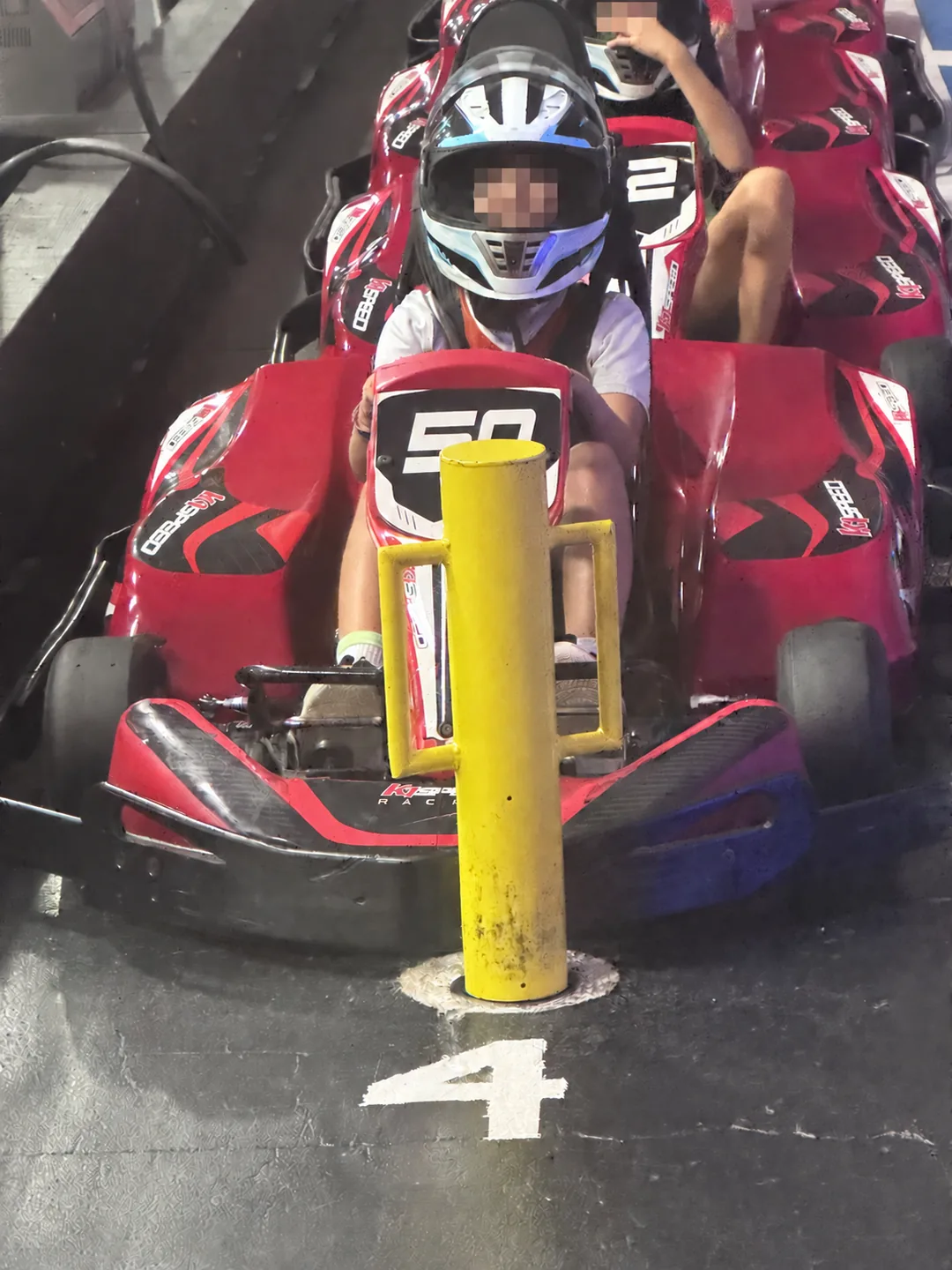 A child racing a red indoor go-kart at K1 Speed Austin; visible children’s faces are obscured for privacy