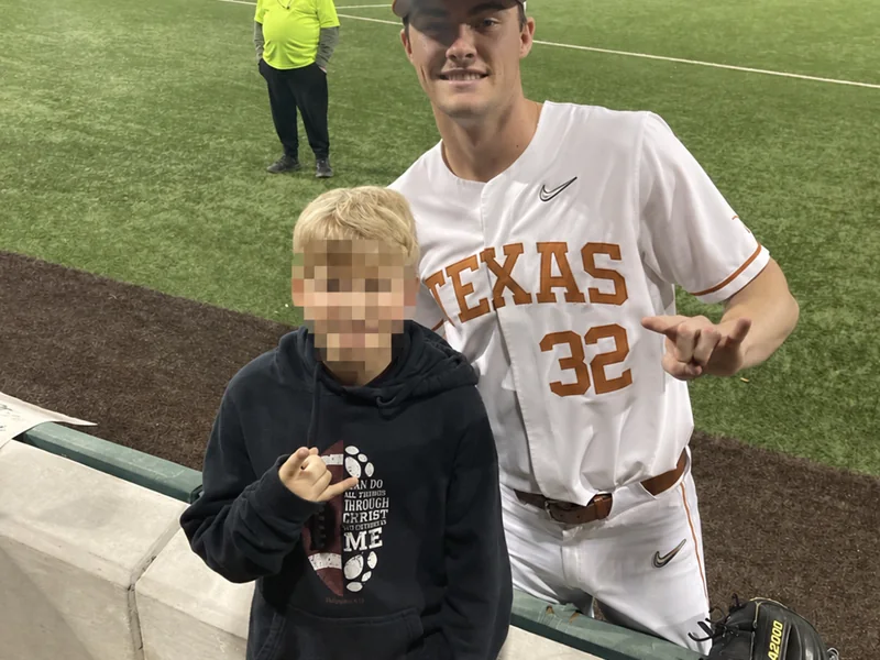 A child meeting a Texas Longhorns baseball player after a game; the child’s face is obscured for privacy