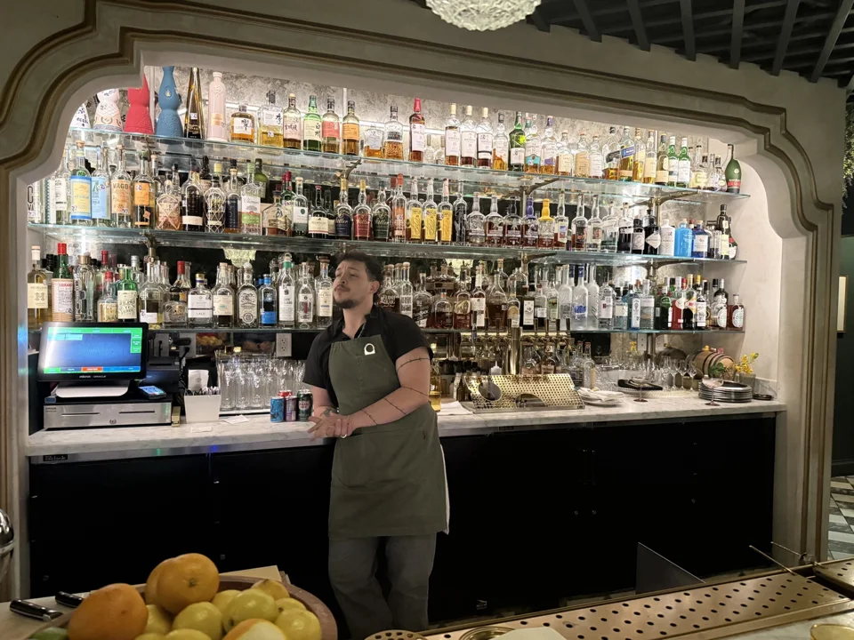 Bartender behind the illuminated bar at Lutie’s